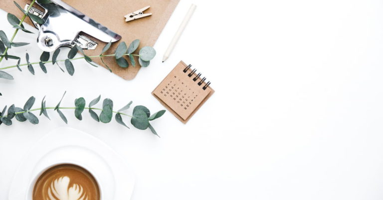 office desk top with calendar and coffee mug