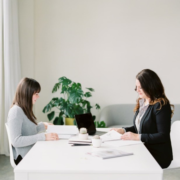 two women sitting at table facing each other.