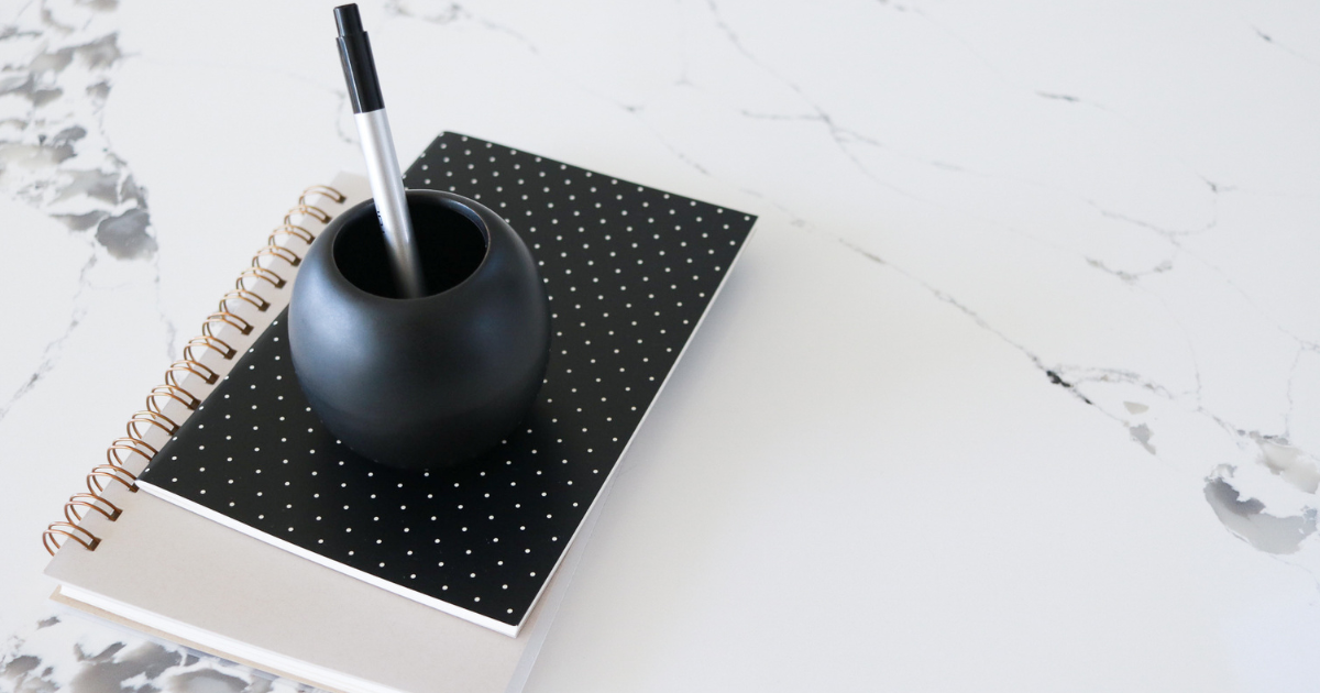 A black polka dot notebook with a pen resting on top.