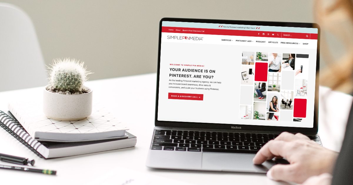 A woman's hand resting on the mouse of a laptop open to a website page.