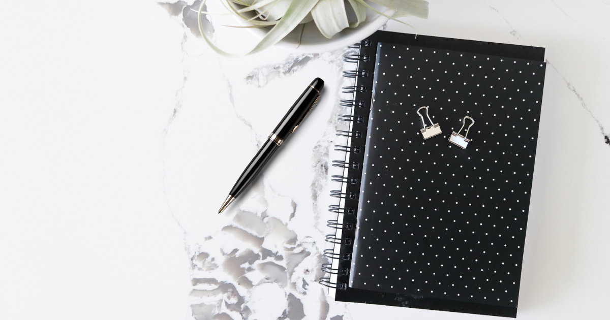 Two paper clips sitting on top of a black polkadot notebook.